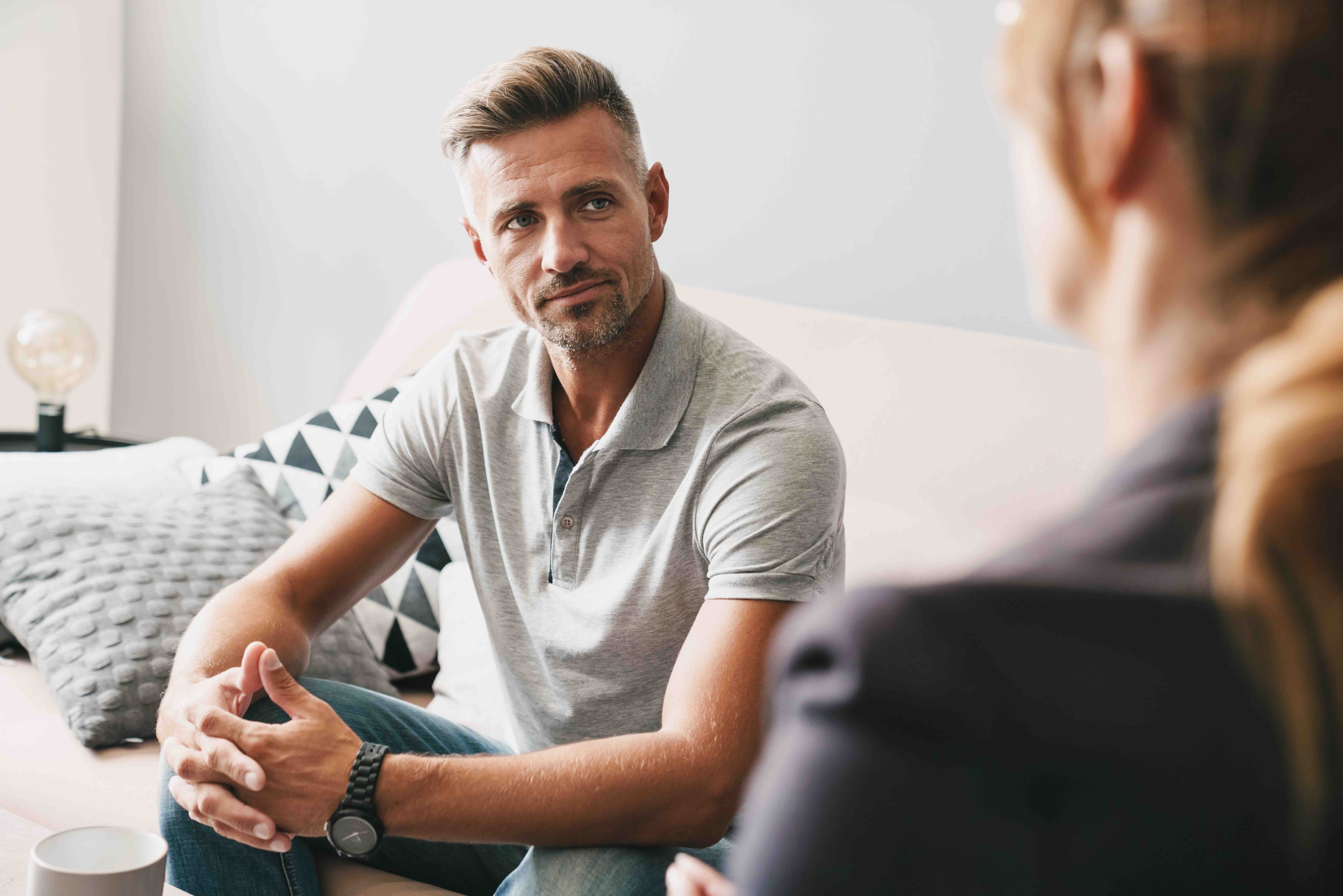 Photo of confident focused man having conversation with psychologist in room